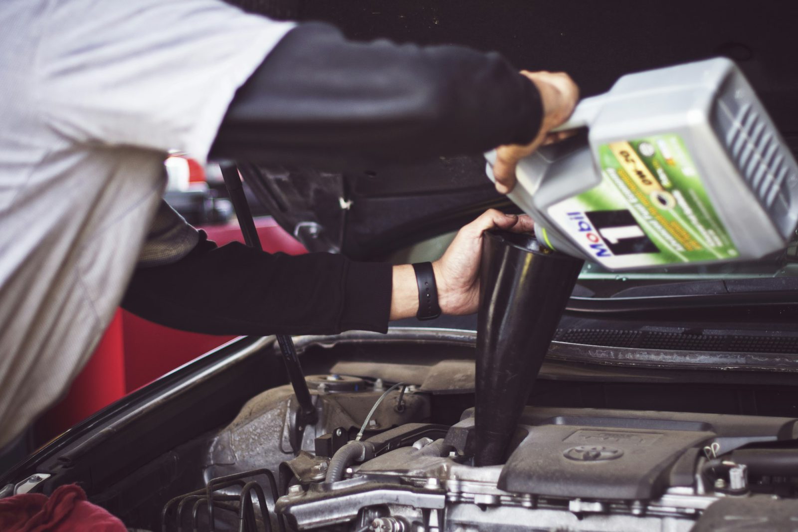 Pouring fresh oil into an engine during a service