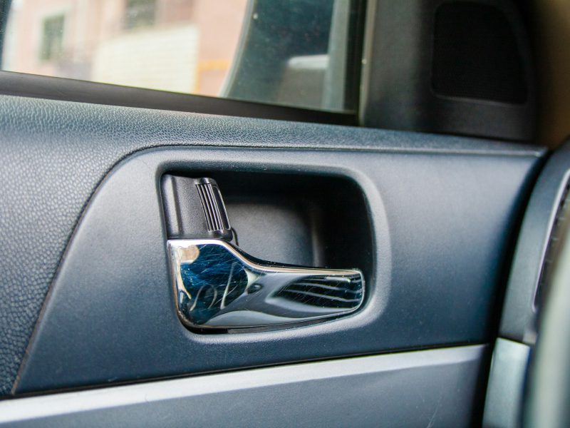 Close-up of a chrome interior door handle and lock switch on a modern car door panel