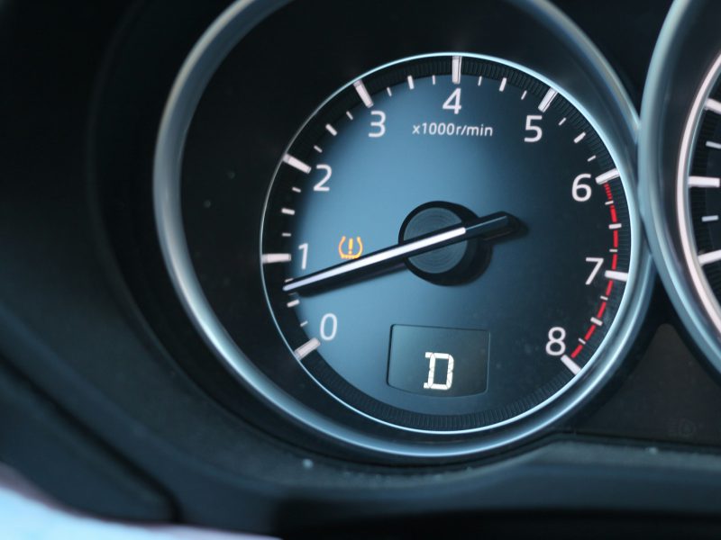 Car dashboard with tachometer, drive mode indicator, and warning light