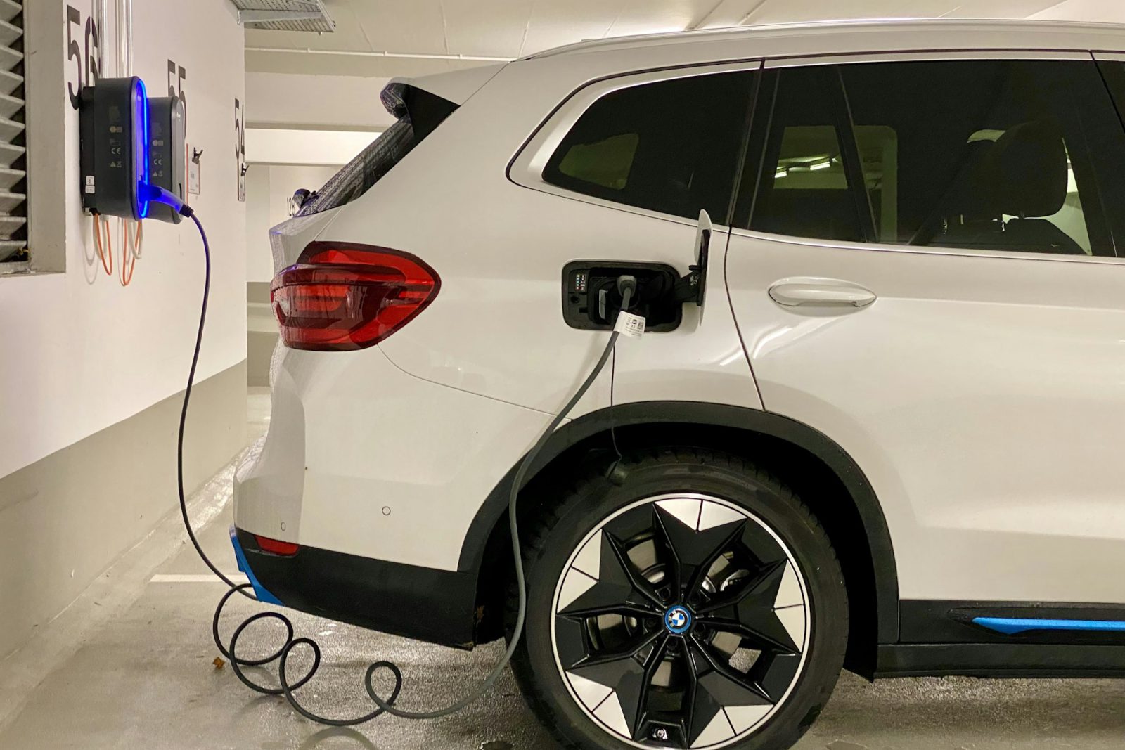 White electric SUV plugged into a garage wall charger