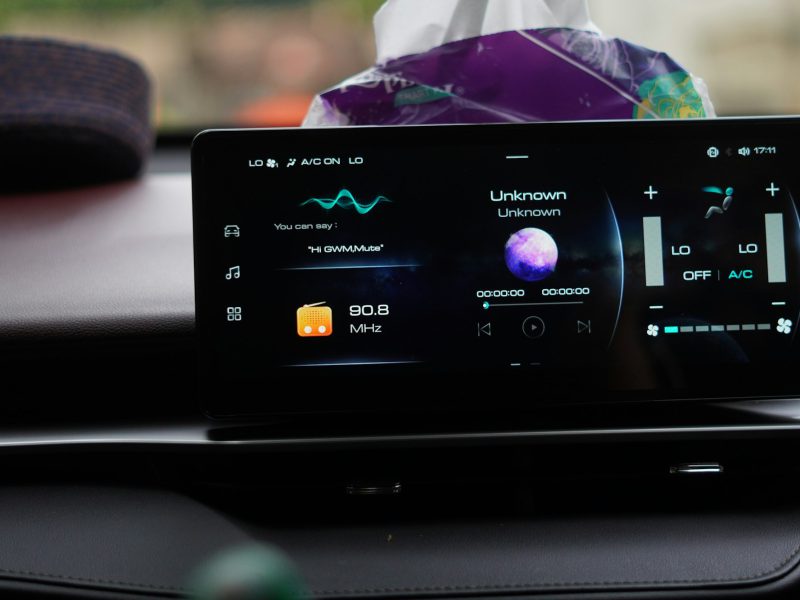 A digital car dashboard display showing radio frequency and climate control settings