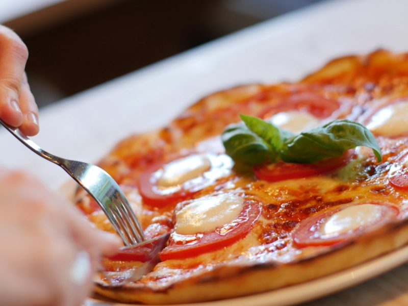A pizza about to be sliced on a white plate