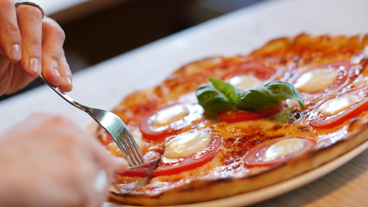 A pizza about to be sliced on a white plate