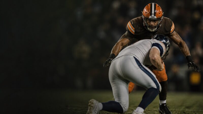 A linebacker in brown and orange arrives on a tackle.