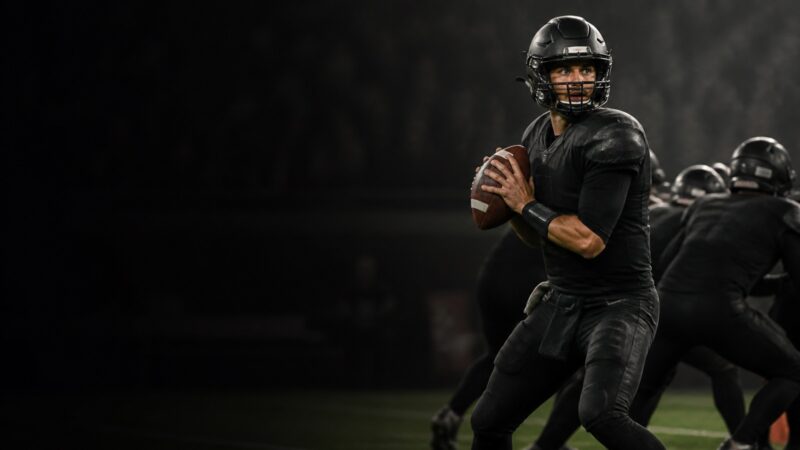 A quarterback set in the pocket scans downfield behind his line.