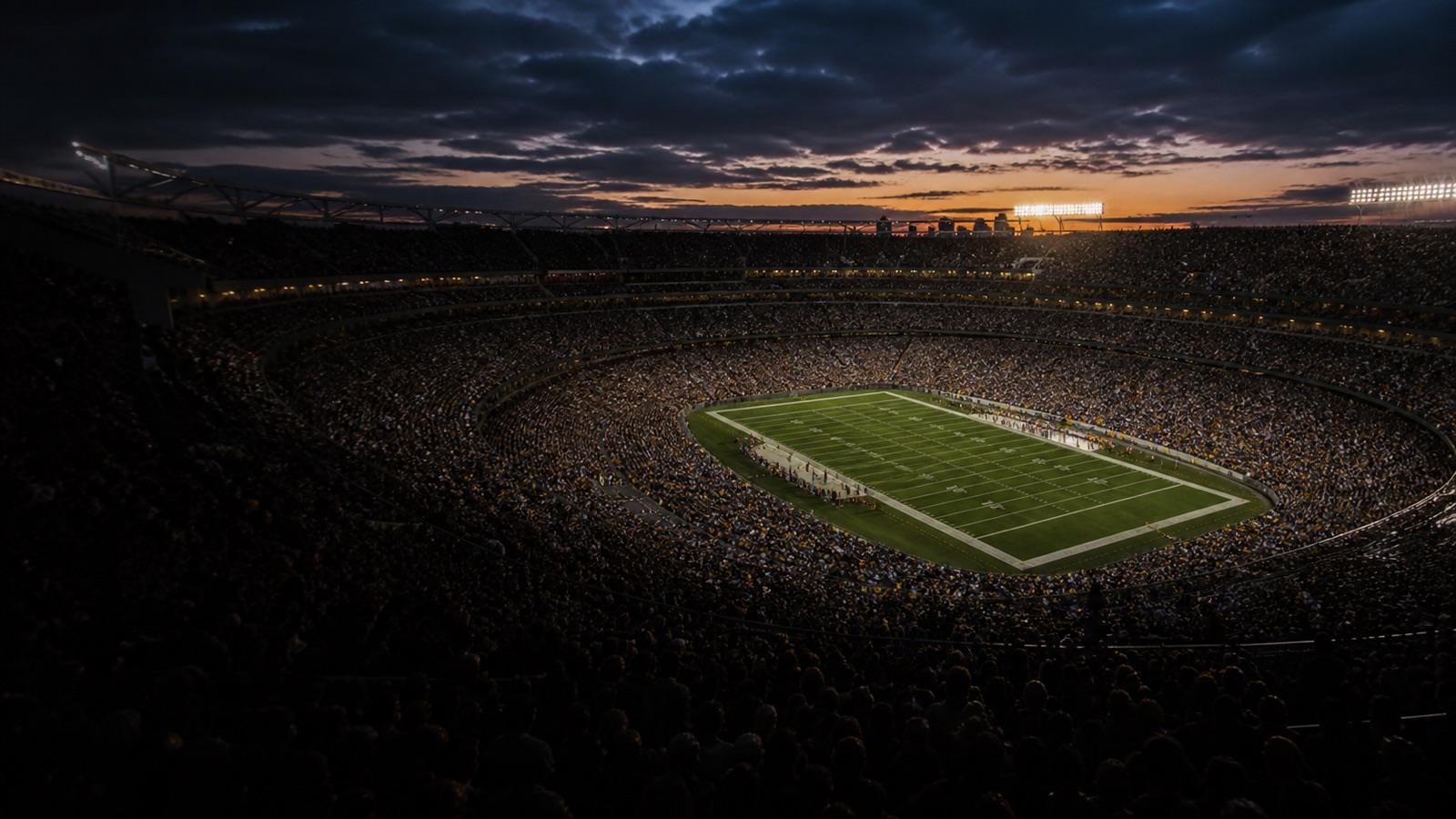 A packed stadium bowl at dusk as the floodlights come up.