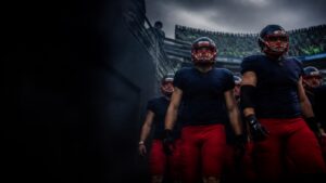 Visiting players in navy and red walk out into a loud home stadium.