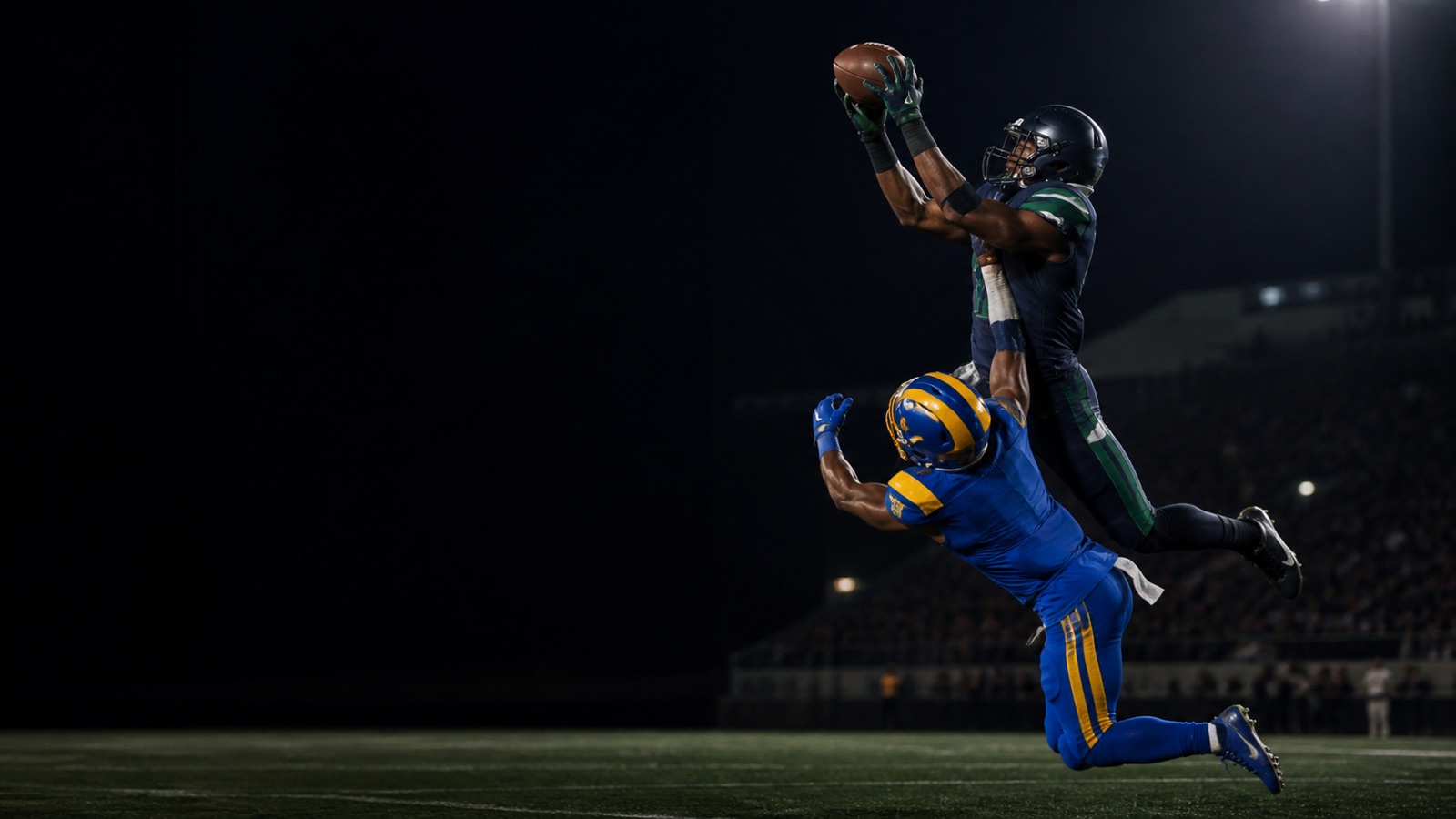 A receiver in navy and green takes a contested catch over a defender in blue and gold.